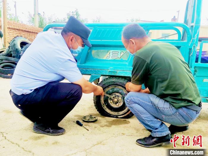 賽旦與民警共同維修三輪摩托車。　依力哈木江 攝