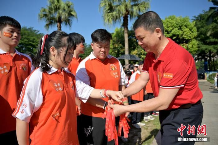 資料圖：廣西華僑實(shí)驗(yàn)高中的教師為高三學(xué)子系上紅絲帶，盼望學(xué)子高考必勝。 俞靖 攝